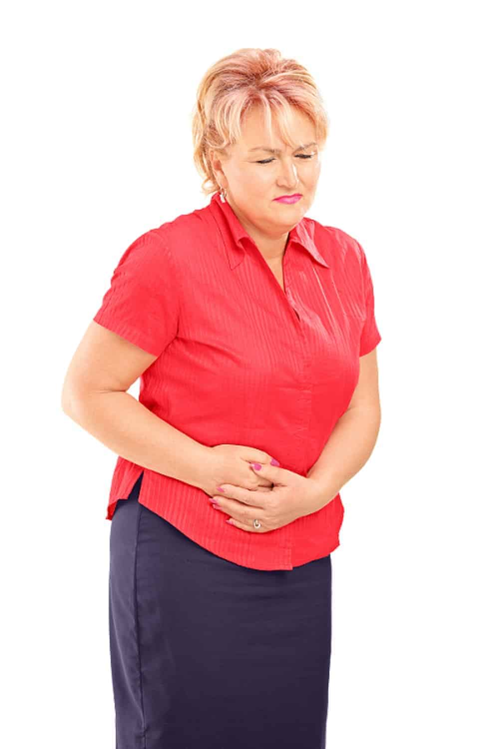 Woman holding her stomach in pain against a white background.