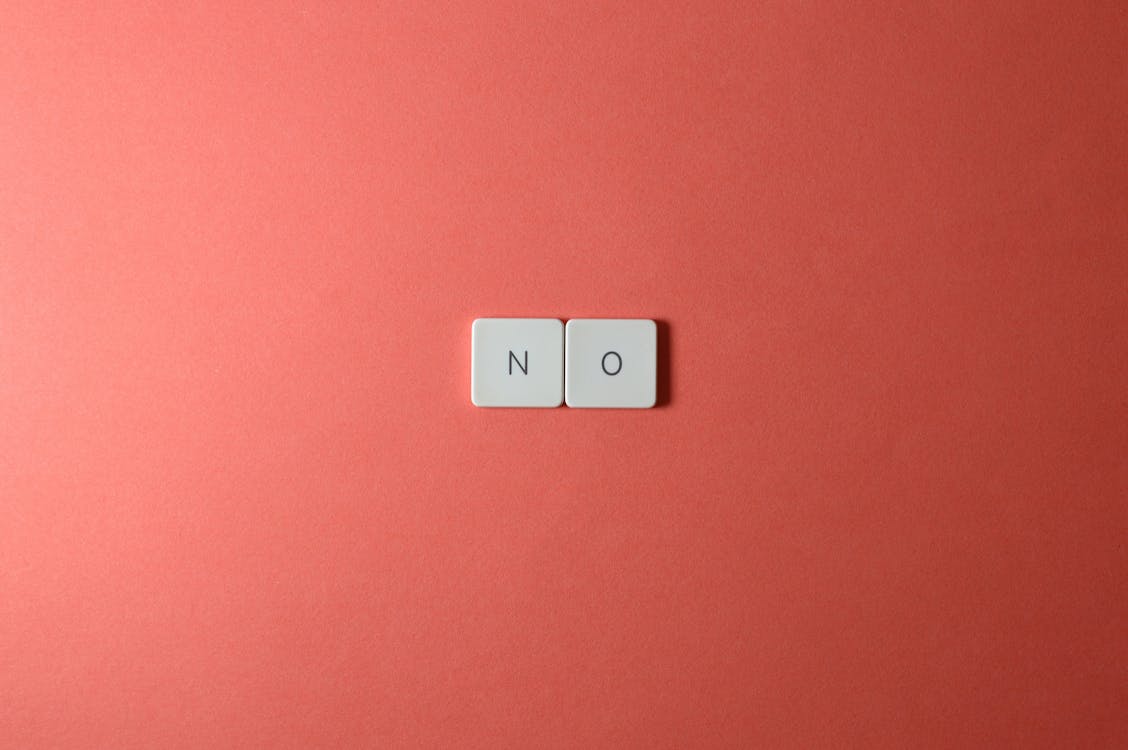Letter tiles spelling no on a pink background.