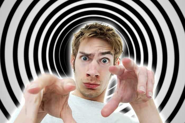 Man posing hypnotically in front of a black and white spiral background.